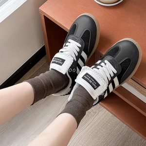 Close-up of retro black leather sneakers with white stripes and gum soles on a shelf