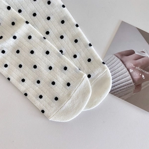 Détail de chaussettes en tricot côtelé crème à pois noirs avec couture fine aux orteils