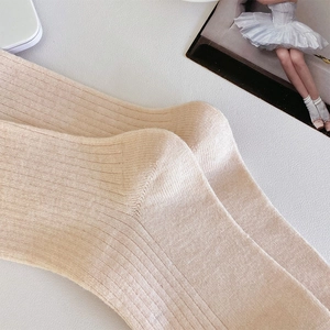 Détail macro de la maille côtelée beige clair et du talon renforcé sur chaussette en laine