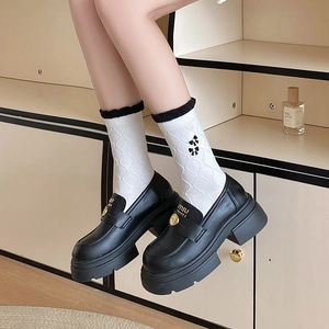Black platform loafers with white embroidered bow socks and frilled trim details