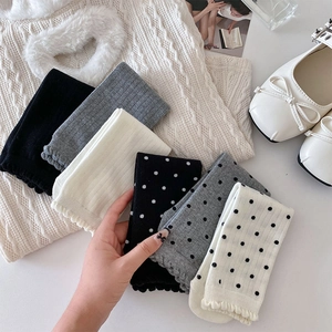 Détail de chaussettes en coton avec pois, rayures verticales et bords ondulés