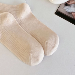 Détail de chaussettes en laine tricotées à côtes crème avec une texture douce et élégante