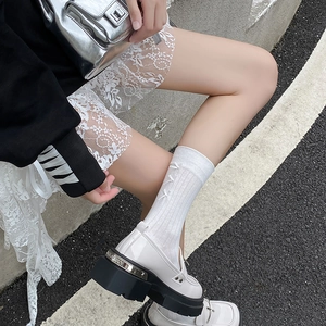 Detail of white ballet-style ribbed socks with cute bow accents and platform loafers