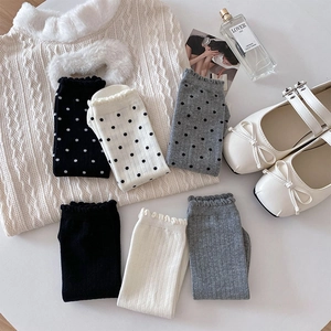 Détail de chaussettes mi-mollet en coton avec pois, rayures verticales et bords volantés