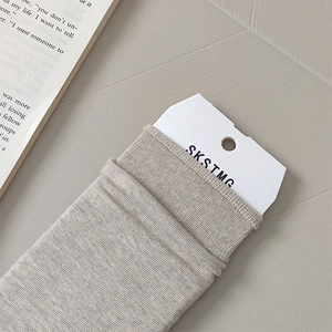 Close-up of light grey ribbed knit socks with a minimalist brand tag on wooden surface