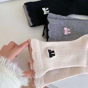 Détail de la texture en maille et broderie nœud sur chaussettes en laine à bords ondulés