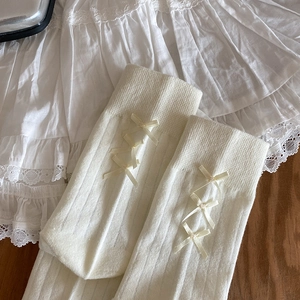 Detail of white rib-knit socks featuring elegant yellow silk ribbon bows and lace trim