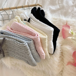 Close-up of sweet pastel knit socks with lace edges and delicate bow decorations