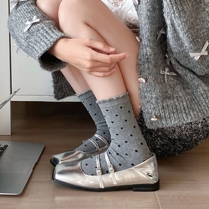 Vue latérale de babies argentées à double bride avec des chaussettes grises à pois