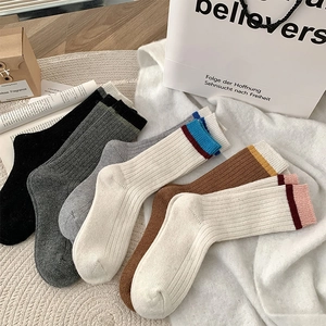 Détail de chaussettes en laine à côtes aux tons neutres avec rayures colorées au bord