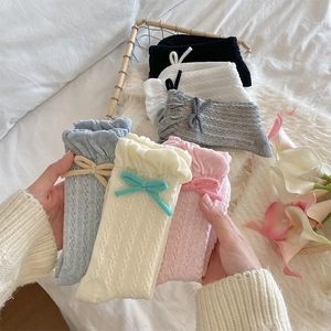 Detail of cable knit socks with sweet bow accents and scalloped edges in multiple soft colors
