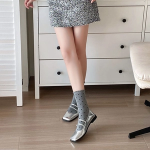 Gros plan sur des ballerines Mary Jane argentées à bout carré et chaussettes à pois