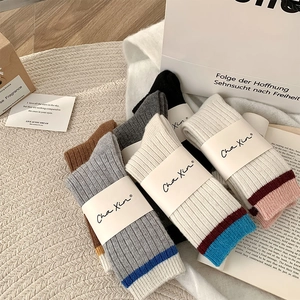 Détail de chaussettes en laine à côtes contrastées montrant la texture chaude et le tricot