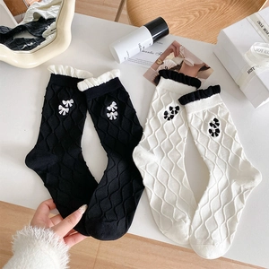 Close-up of bow with pearls on ruffled rib knit mid-calf socks in black and white