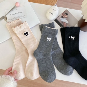 Détails de chaussettes en laine avec broderie nœud et bordure à volants festonnés chic