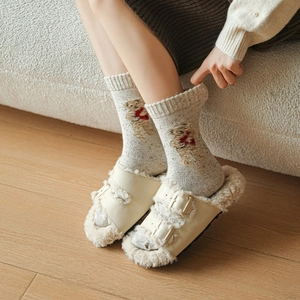 Beige faux fur double buckle slides with warm wool bear socks on wooden floor