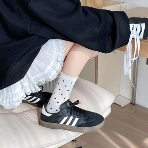 Chaussettes à pois portées avec des baskets noires et une jupe en dentelle chic