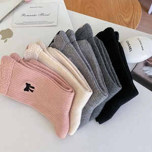 Détail de chaussettes en laine tricotée avec broderie nœud et texture à côtes verticales