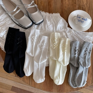 Detail of ballet style socks with bow accents in black, white, beige and grey colors