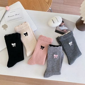Détail de chaussettes en laine montrant des nœuds brodés et une texture côtelée en cinq couleurs