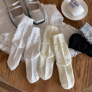 Detailed view of ballet style white mid-calf socks with delicate ribbon bow and rib knit