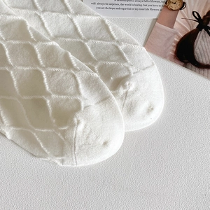 Macro shot of white diamond-patterned knit cotton socks with delicate lace cuffs
