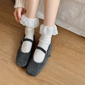 Close-up of dark grey wool Mary Janes paired with white floral lace trim socks