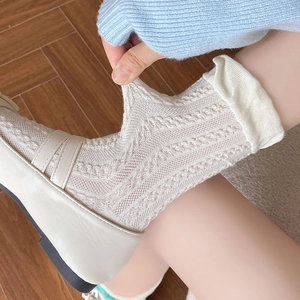 Detailed view of white hollow knit socks with delicate patterns and beige loafers