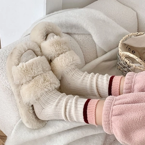 Détail de chaussettes en laine crème à rayures contrastées roses et pantoufles douillettes