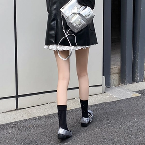 Detail of black knee-high socks with side criss-cross ribbons and bow in ballet style
