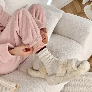Gros plan d'un vêtement de détente rose avec pantoufles et chaussettes en laine