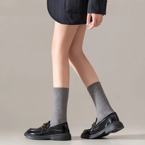Classic black patent leather loafers with gold horsebit buckle and grey wool socks