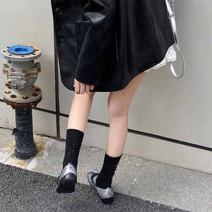 Detail of black crew socks with silk ribbon bow ties paired with silver glitter flats