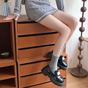 Détail de chaussettes grises côtelées avec des mocassins noirs en cuir verni
