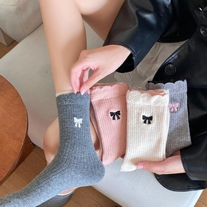 Détail de broderie nœud et bords dentelle ondulés sur des chaussettes en laine