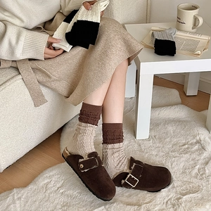Detail of warm brown suede clogs with faux fur lining and knitted patchwork socks