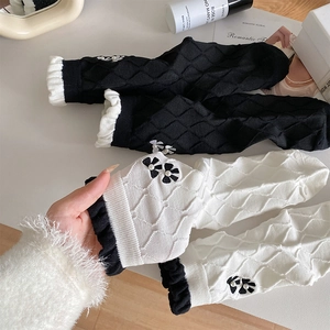 Detailed view of diamond pattern knit socks with ruffled edges and pearl flower embroidery