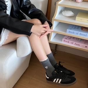 Détail de chaussettes en tricot gris avec broderie de nœud blanc pour un style d'hiver doux