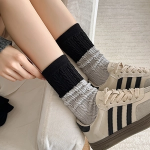 Detail view of contrast color cable knit crew socks showing gray and black textures