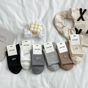 Flat lay of cotton mid-calf socks in various colors with heart embroidery and tags