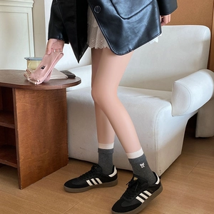 Détail de chaussettes en laine avec broderie nœud blanc et bords côtes sur le pied