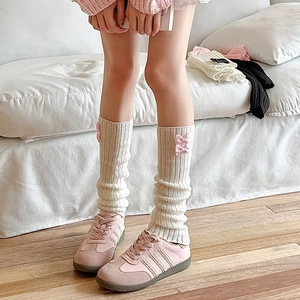 Détail de jambières en maille crème avec nœuds roses et texture côtelée style Lolita