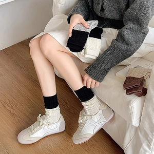 Detailed knit texture of vintage contrast color crew socks with ribbed cuffs on wooden floor