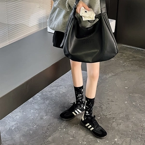 Detail of trendy black crew socks with white polka dots paired with casual black sneakers