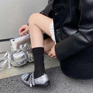 Silver glitter Mary Jane shoes paired with black bow mid-calf socks in a Y2K aesthetic