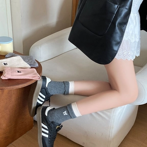 Détail de chaussettes en laine tricotées avec broderie de nœud et bordure blanche douce