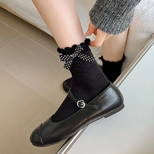 Close-up of black frilly socks with polka dot bows paired with Mary Jane shoes