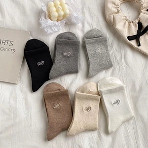 Close-up of mid-calf socks in six colors featuring Hi heart embroidery in a cozy setting