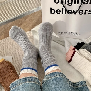 Détail de chaussettes côtelées en laine grise avec rayures contrastées bleu et blanc