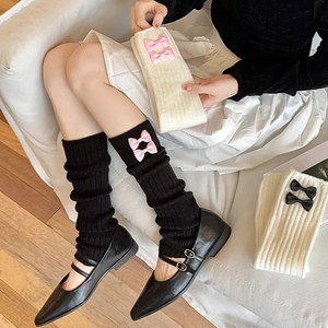 Détail de la maille tricotée et des nœuds roses sur ces jambières style balletcore